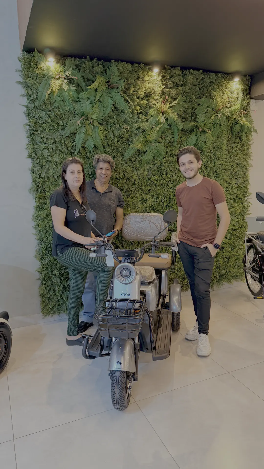 Clientes recebendo triciclo elétrico MOTOCHEFE no showroom